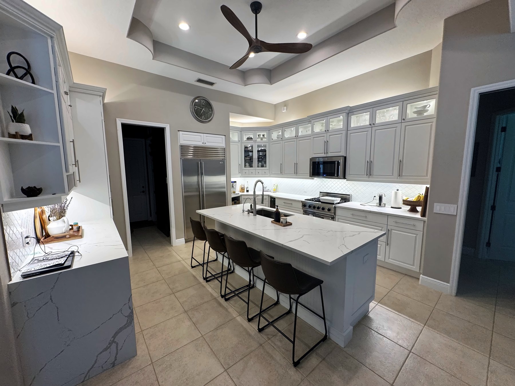 Kitchen with recessed lights, under-cabinet and glass-cabinet LED lighting and a ceiling fan over the island