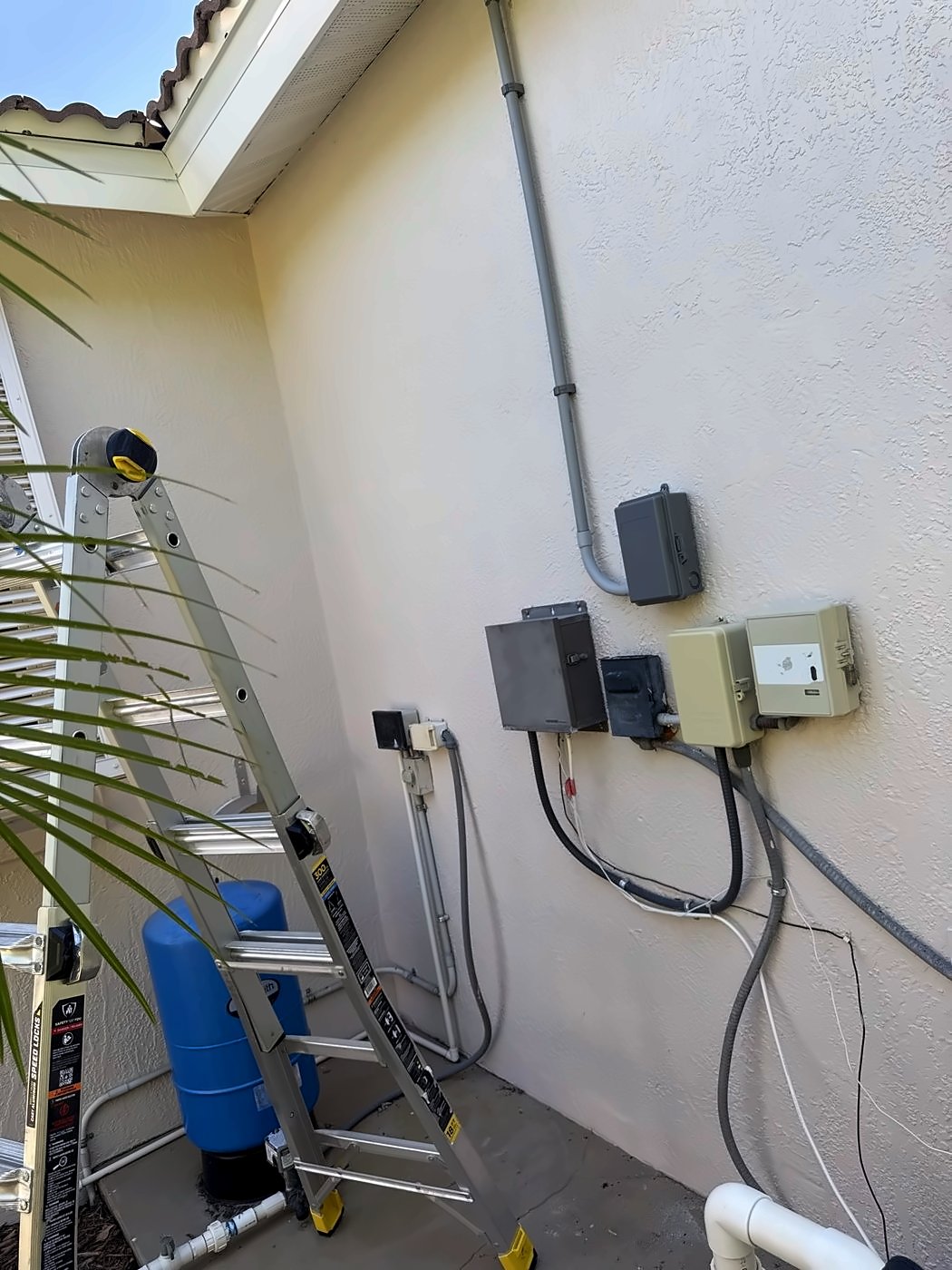 Equipment wall with disconnects, controls and conduit beside a home
