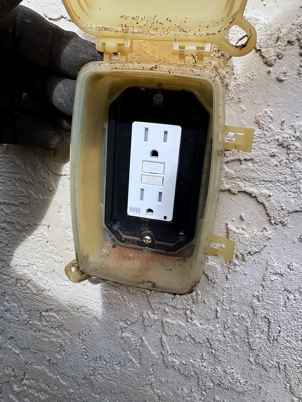 GFCI receptacle under a weatherproof in-use cover on a stucco wall